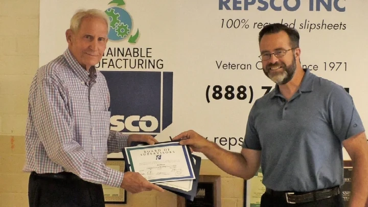 Paul Bennett Jr, President holding a certificate with one other.