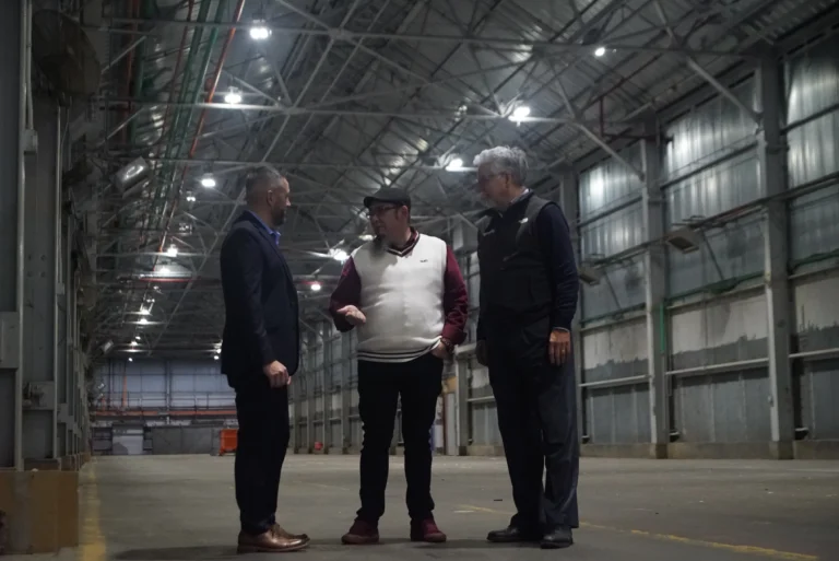 Three people on the factory floor conducting a meeting.